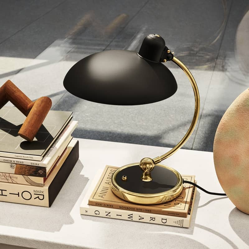 Eine elegante Tischlampe in schwarz-gold steht auf einem Buch